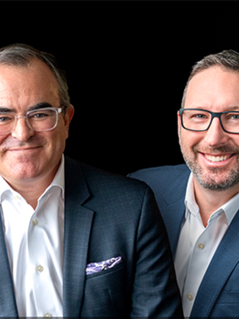 Quatre personnes en tenue professionnelle portant des vestons et chemises blanches, posant devant un fond noir.