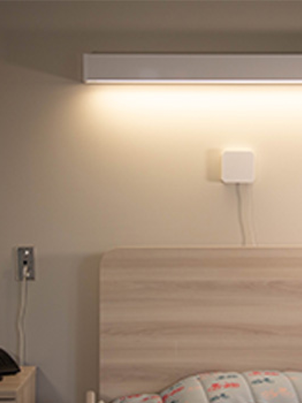 Dispositif mural de surveillance installé au‑dessus d’un lit dans une chambre de soins.