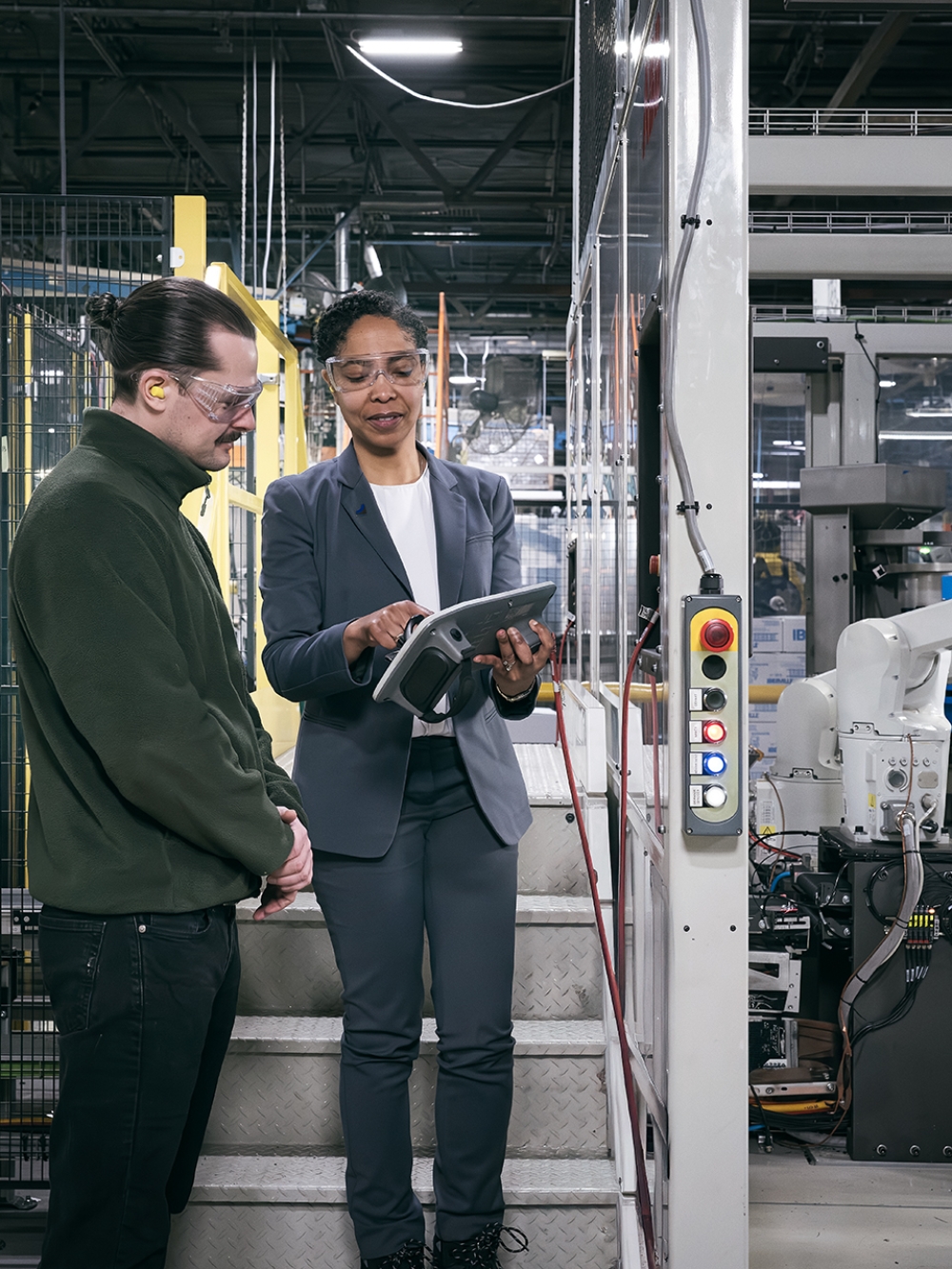 Deux employés et un robot dans une usine