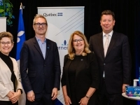 Groupe de personnes debout devant des panneaux portant les logos de Danone et du gouvernement du Québec, avec une table présentant des produits de yogourt Oikos au premier plan.