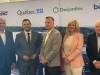 Groupe de personnes posant devant une bannière avec les logos de Manac, Québec, Desjardins et BDC lors d’une annonce officielle.